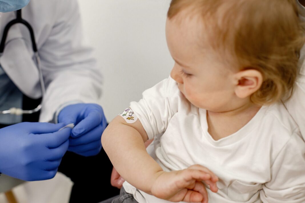 Cropped photo of a boy's shoulder with stick band-aid vaccinatio
